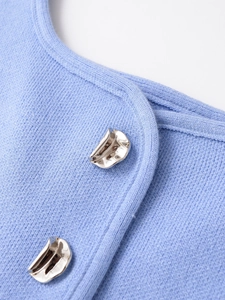 Macro detail of light blue knit top featuring irregular wavy silver metal buttons