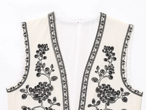 Gros plan détaillé des broderies noires sur le gilet sans manches avec étiquette S