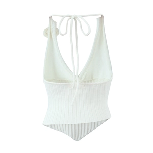 Close-up of white knit halter top featuring a deep V-neck and delicate flower detail