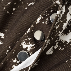 Dettaglio ravvicinato di bottoni metallici su tessuto tie-dye per completo streetwear