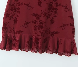 Detailed close-up of burgundy floral velvet burnout mesh fabric and ruffle hem