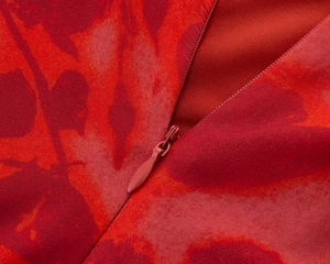 Close-up of the invisible zipper and red floral chiffon fabric on a mini dress