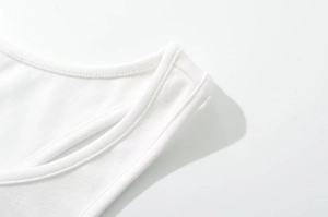 Dettaglio ravvicinato della scollatura e cuciture di un top bianco in cotone a coste
