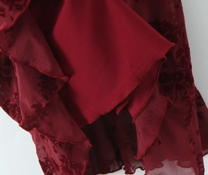 Macro detail of red floral velvet flocking on mesh fabric with layered ruffle hem