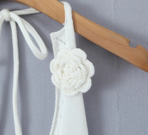 Macro shot of white knitted top featuring handcrafted 3D camellia flower on the strap