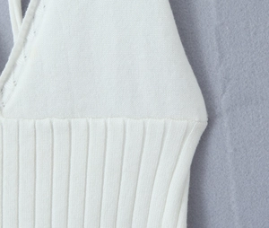 Detail of white knit top showing elastic ribbed texture and smooth stitching craft