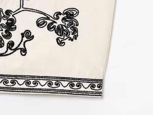 Vue détaillée des broderies botaniques noires sur un gilet sans manches en lin beige