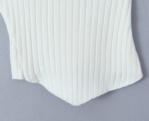 Detail of white ribbed knit top featuring a unique pointed irregular hemline and stitching