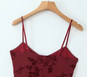 Detail of burgundy floral jacquard fabric with adjustable thin straps and delicate stitching