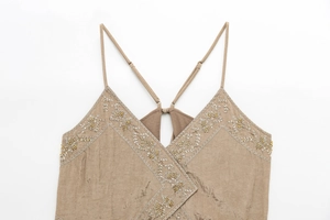Close-up of adjustable spaghetti straps and gold floral embroidery on the V-neck camisole