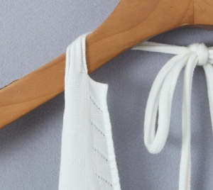 Detail of white hollow-out knit halter top featuring delicate texture and tie straps