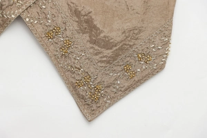 Macro detail of silk-like brown fabric with exquisite silver and gold floral embroidery