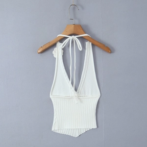 Close-up of a white knit halter top with deep V-neck, 3D floral accent and ribbed texture