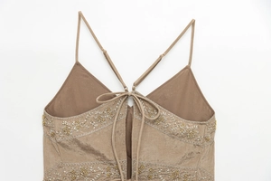 Close-up of intricate floral beadwork and cross-back straps on khaki silk camisole top