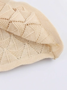 Close-up of cream short-sleeve knit top with geometric hollow triangular crochet pattern