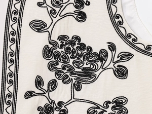Détails de broderie florale ethnique noire sur un gilet d'été sans manches blanc