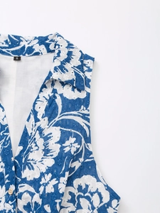 Détail de l'encolure en V avec broderie florale bleue et boutons blancs sur la robe