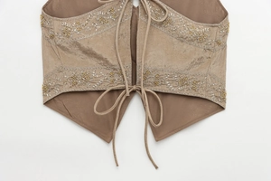 Detail of vintage embroidered brown vest featuring silver diamond patterns and golden sequins