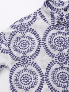 Detailed close-up of purple floral embroidery and eyelet design on a white shirt