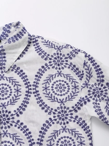 Detail of white cotton blouse showing intricate purple floral eyelet embroidery and texture