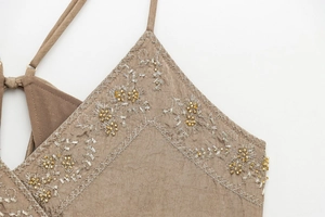 Close-up of vintage brown camisole featuring intricate floral embroidery and beadwork