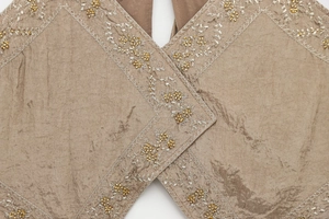 Detail of V-neck camisole with silver embroidery and gold beads on pleated fabric