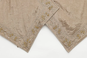 Detail of champagne satin top featuring intricate floral embroidery and gold beadwork