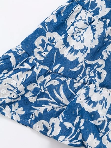 Détail de la broderie anglaise florale bleue et du tissu léger en coton de la robe