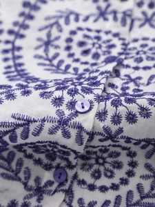 White long-sleeved shirt featuring blue floral embroidery and hollow-out lace details