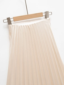 Detail of elegant beige satin pleated skirt with elastic waist and silk luster