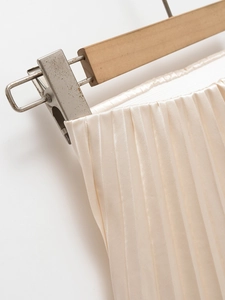 Close-up of champagne pleated satin skirt showing fine texture and glossy fabric