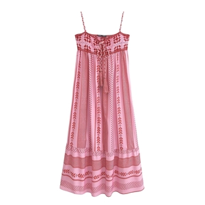 Détail de robe longue bohème rose avec broderie rouge et liens à pompons au cou