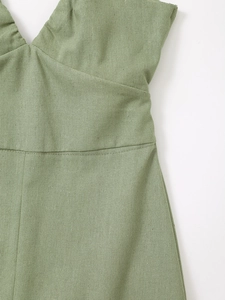 Détail macro de la texture du lin vert sauge sur le col en V et la taille haute de la robe