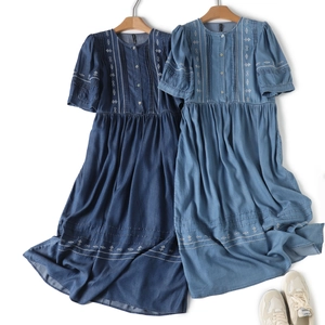 Detail of embroidered floral patterns on blue denim dresses with pleated chest accents