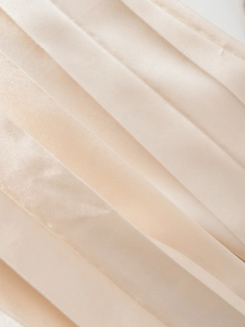 Close-up of pleated champagne satin fabric with elegant silk sheen and texture