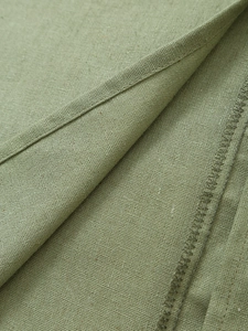 Vue macro détaillée du tissu en coton-lin vert herbe avec des coutures et un ourlet soignés