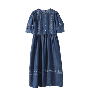 Close-up of white geometric embroidery and button detail on dark blue denim dress