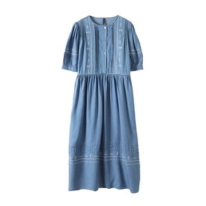 Detail of light blue denim dress showing ethnic white embroidery and buttoned neckline