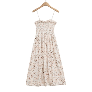 Close-up of smocking details and floral print on a white summer dress with thin straps
