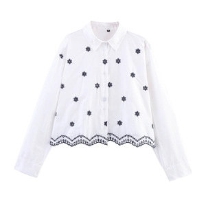 Détail de chemise blanche avec broderie florale noire et ourlet festonné en dentelle
