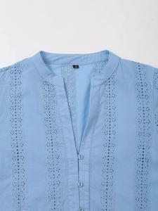 Close-up of light blue shirt featuring V-neck and vertical eyelet lace embroidery details