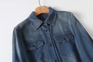 Detail shot of vintage denim shirt collar with metallic buttons and flap pocket texture