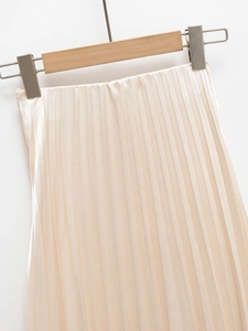 Detail view of champagne satin pleated skirt with fine vertical pleats and smooth finish