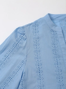 Detail of light blue shirt featuring intricate lace embroidery and V-neckline texture