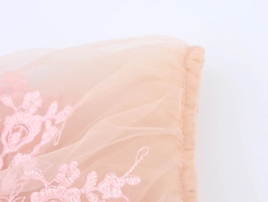 Detailed macro view of pink floral embroidery and delicate mesh fabric on the summer top