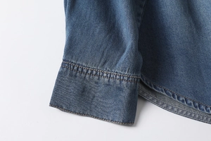 Macro detail of high-quality double-stitch sewing on blue denim shirt cuffs and hem