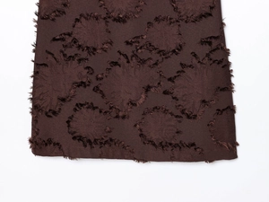 Gros plan sur le tissu texturé marron foncé avec détails floraux en relief