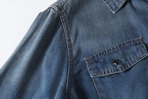 Detailed macro shot of vintage blue denim shirt featuring orange topstitching and chest pocket