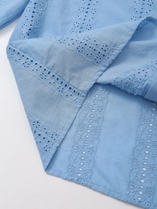 Detail of light blue cotton top showing intricate eyelet embroidery and wave texture