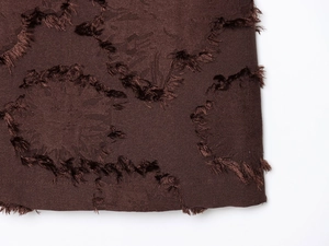 Gros plan de la robe mini marron foncé avec texture à franges et détails tissés